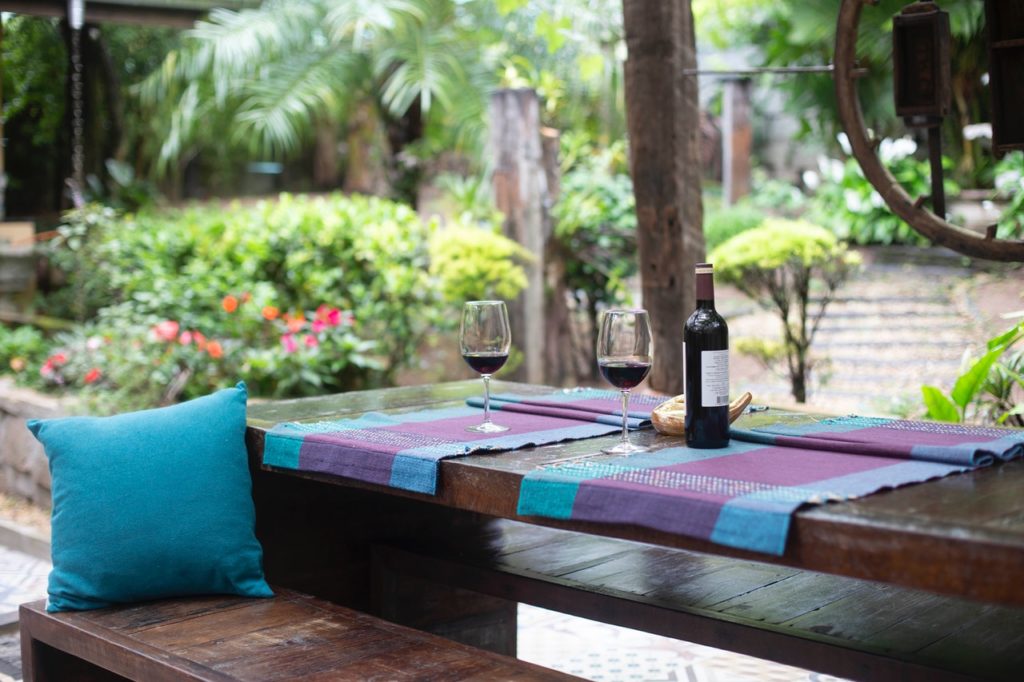 Vinflaske står på terrasse til sommerhus med palmer i baggrunden