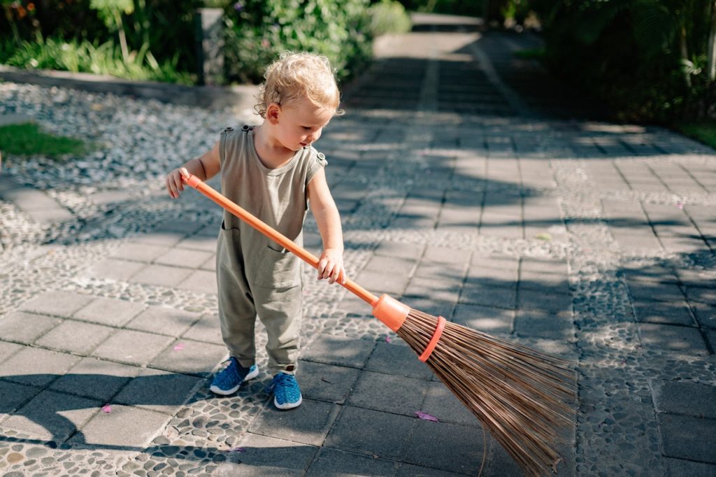 Barn gør rent i haven med kost